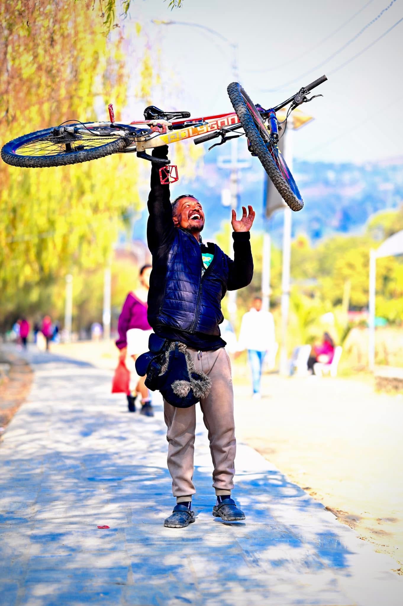 Lifting a bicycle overhead on a sunny park path