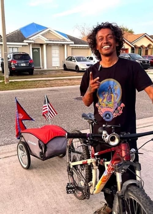 Man riding bike with flag trailer on suburban street