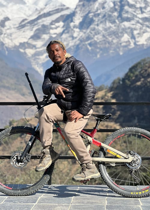 Man posing with mountain bike against snowy peaks