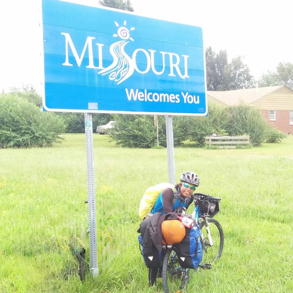 Cyclist poses at Missouri welcome sign