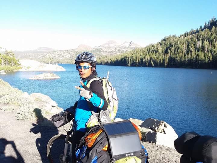 Cyclist posing at mountain lake with alpine scenery